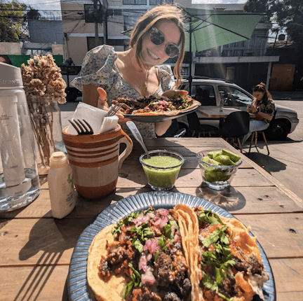 Cat poses with a plate of several tacos