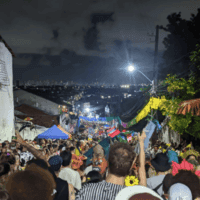 Crowd seen all the way down a street with panoramic city views in the distance