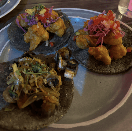 A plate of 3 tacos on a dark base