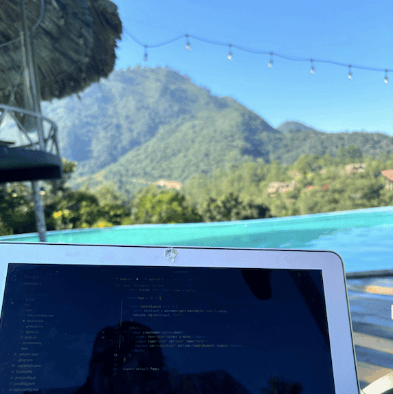 Laptop pictured in front of an infinity pool with mountain view
