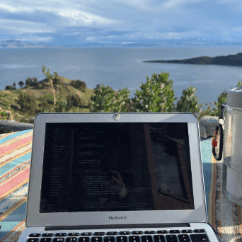 Photo of a laptop on a table with a view of a lake