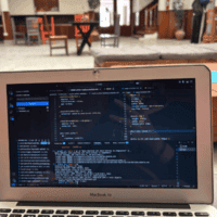 Laptop pictured in a hostel with chairs in the background